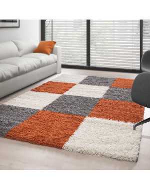 Hoogpolig vloerkleed met een terracotta-wit-grijs geblokt patroon.